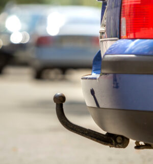 blue-car-parked-sunny-street-red-stop-lights-hook-dragging-trailer-tow-hitch-towbar